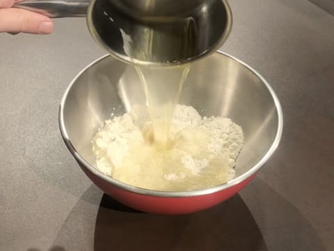La préparation bouillante dans la casserole est versée sur la farine dans le cul de poule