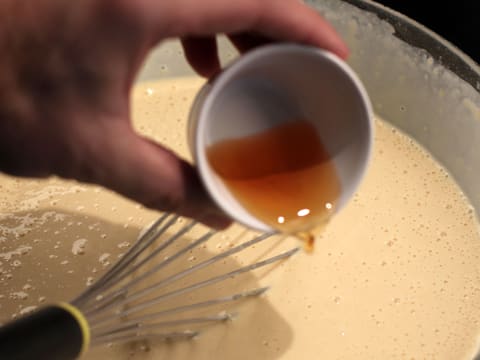 Ajout du rhum dans la pâte à crêpes, dans le saladier