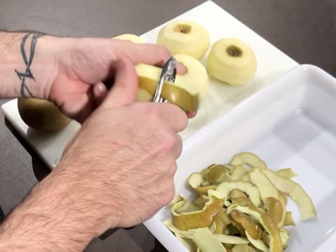 Des pommes sont épluchées à l'aide d'un éplucheur