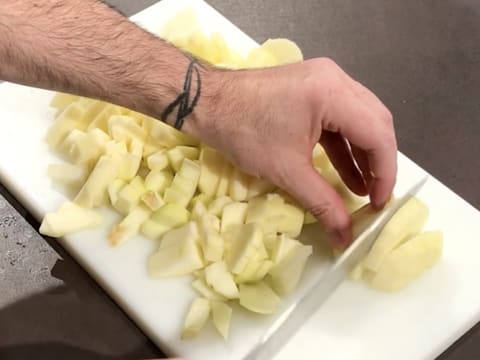 Les pommes sont coupées en petits morceaux avec un couteau, sur une planche à découper