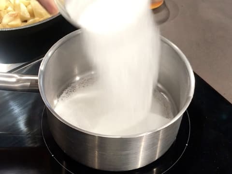 Le sucre en poudre est versé en pluie fine dans une casserole placée sur la plaque de cuisson
