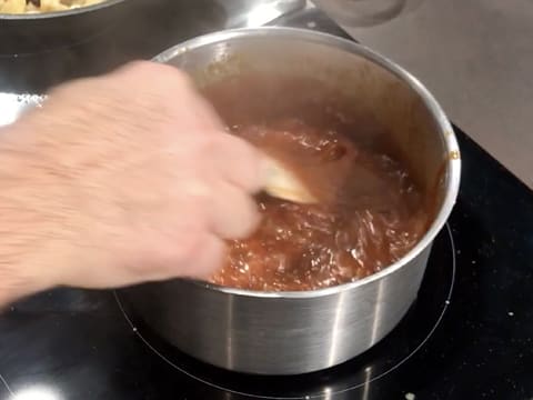 La sauce caramel est en train de cuire dans la casserole, tout en étant mélangée avec la spatule maryse