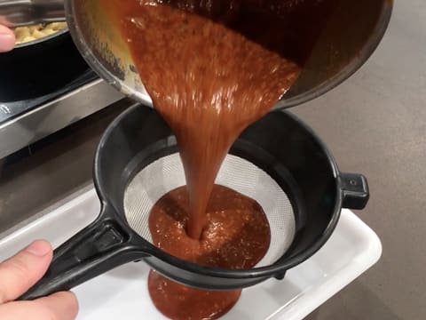 La sauce caramel est passée à travers une passoire tamis au-dessus d'un bac alimentaire