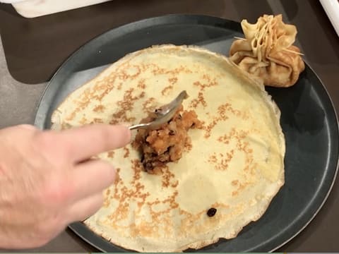 Une seconde crêpe est placée sur la plaque à pâtisserie ronde, avec une cuillère à soupe de compote de pommes versée en son centre