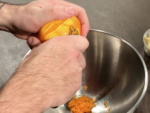 Les zestes d'une orange sont prélevés à l'aide d'un zesteur canneleur, et placés dans un cul de poule