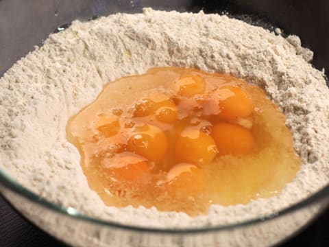 Les oeufs entiers et le sucre en poudre sont ajoutés dans la farine, dans le saladier