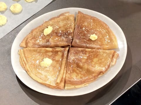 Une noix de beurre d'orange est déposée sur trois crêpes dans l'assiette