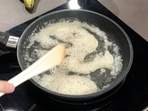 Le beurre et le sucre en poudre sont mélangés dans la poêle à l'aide d'une spatule, et forment un caramel blond