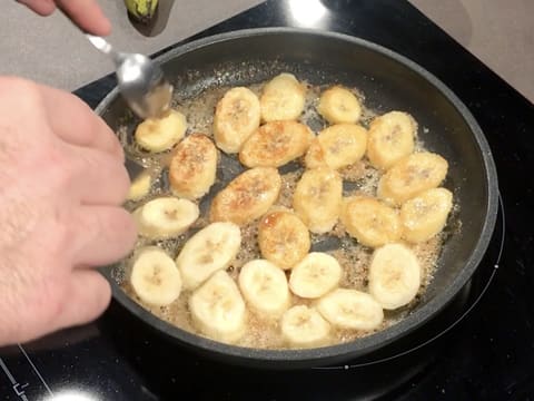 Les rondelles de banane sont retournées sur l'autre face, dans la poêle