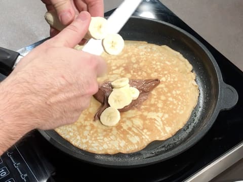 Quelques rondelles de banane crue sont placées sur le chocolat, au centre de la crêpe