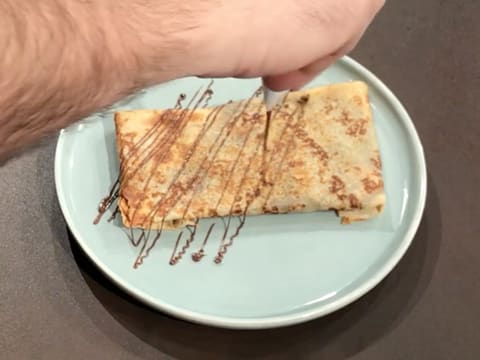 La crêpe sur l'assiette de service est décorée avec des filaments de pâte à tartiner