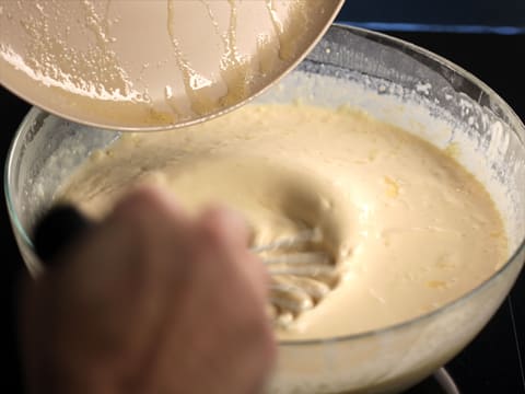 Ajout du beurre fondu dans la pâte à crêpes, dans le saladier, tout en mélangeant au fouet