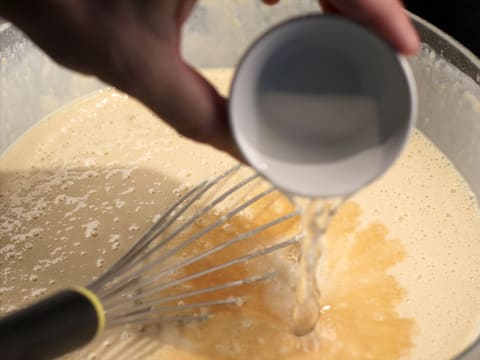 Ajout de l'eau dans la pâte à crêpes, dans le saladier