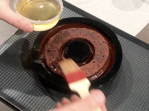 Le biscuit chocolat est punché avec du sirop de punchage et à l'aide d'un pinceau pâtissier