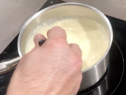 La casserole qui contient la crème est placée sur la plaque de cuisson, et la préparation est mélangée à la spatule