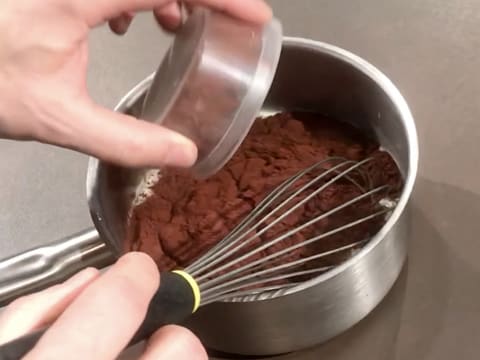 Ajout du cacao en poudre dans la casserole contenant la crème et le fouet