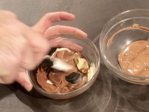 Les fèves de chocolat au lait et de chocolat blanc sont partiellement fondues et sont mélangées ensemble avec la spatule maryse