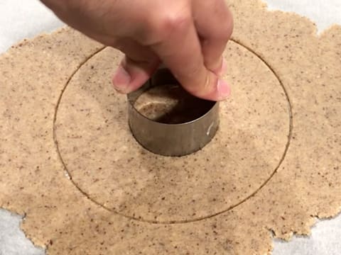 À l'aide de la main, le petit cercle à mousse est pressé sur le centre du grand disque de pâte à streusel noisette