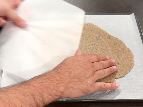 La feuille de papier sulfurisé qui recouvre la pâte à streusel noisette est retirée