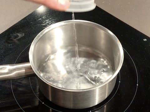 L'eau est versée dans une casserole qui est placée sur une plaque de cuisson