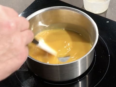 La préparation est en train de cuire dans la casserole, tout en étant mélangée avec une spatule type maryse