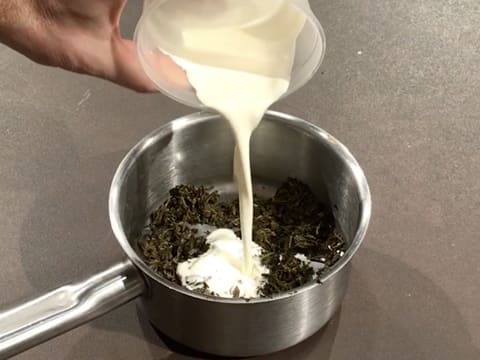 La crème liquide est versée dans la casserole contenant le thé infusé, et qui est posée sur le plan de travail