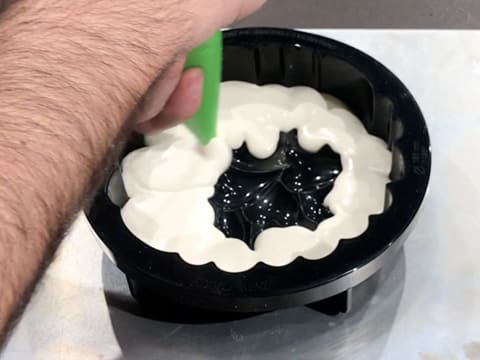 Le bavarois chocolat blanc, vanille, jasmin est poché dans le fond d'un moule en silicone qui est posé sur une plaque à pâtisserie