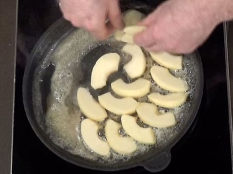 Les lamelles de pomme sont disposées dans le beurre fondu dans la poêle