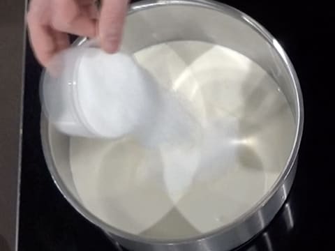 Ajout du sucre en poudre dans la casserole contenant le lait et la crème