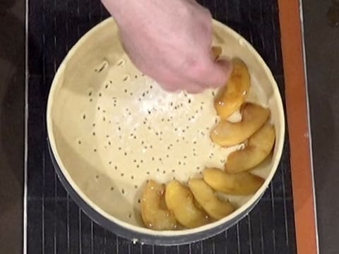 Les lamelles de pomme rôties sont disposées sur la pâte qui est foncée dans le cercle à mousse