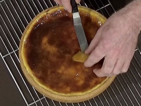 Une lamelle de pomme est déposée sur le flan, avec une petite spatule métallique coudée