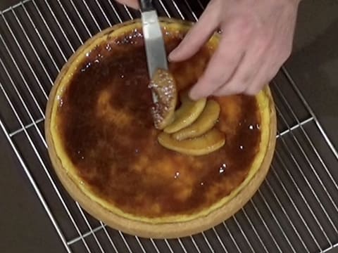 Une quatrième lamelle de pomme est déposée sur le flan, avec une petite spatule métallique coudée