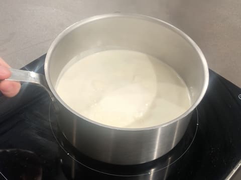 Le lait et la crème entrent en ébullition dans la casserole qui est sur la plaque de cuisson