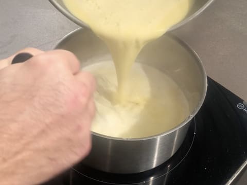 La préparation lactée est transvasée dans la casserole qui contient le restant de lait et de crème, tout en étant mélangée au fouet
