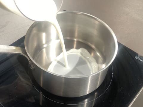 Le lait est versé dans une casserole qui est posée sur la plaque de cuisson