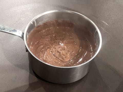 Obtention de la crème pâtissière chocolatée dans la casserole posée sur le plan de travail