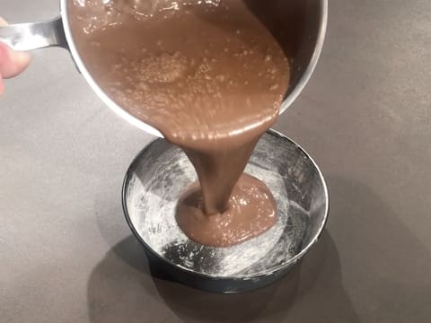 La crème au chocolat est versée dans le moule à manqué rond et chemisé de beurre et de farine