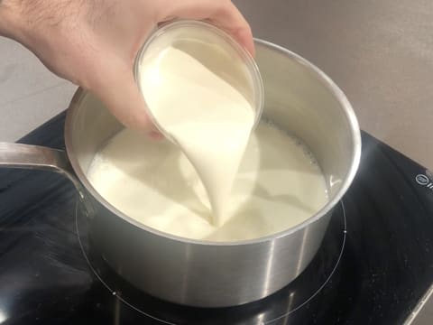 Ajout de la crème fleurette sur le lait dans la casserole qui est posée sur la plaque de cuisson