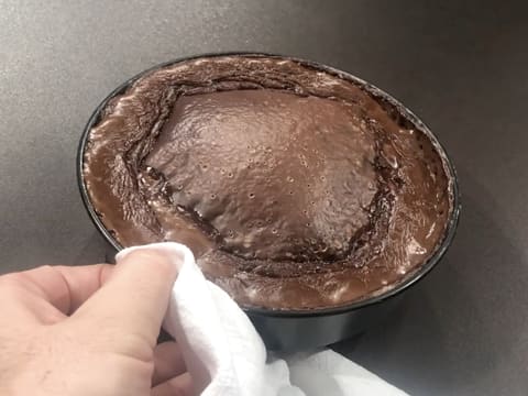 Le moule à manqué rond qui contient le flan pâtissier au chocolat cuit, est posé sur le plan de travail