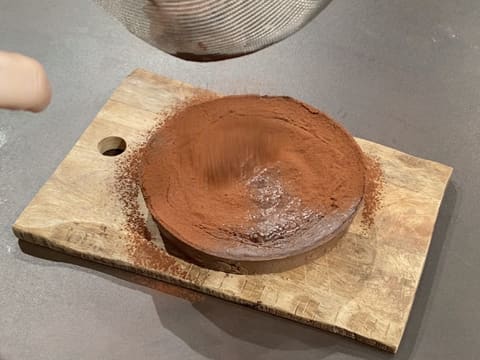 Le flan pâtissier au chocolat sans pâte est placé sur une planche à découper en bois et il est saupoudré de cacao en poudre