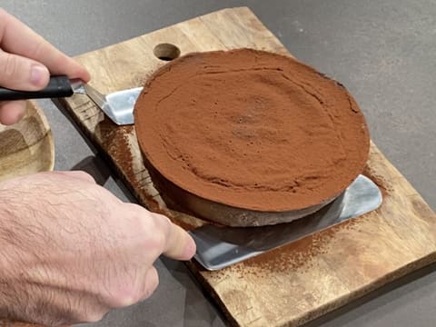 Le flan pâtissier au chocolat sans pâte est soulevé à l'aide de deux spatules métalliques coudées