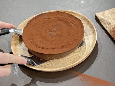 Le flan pâtissier au chocolat sans pâte est déposé sur son plat de servie à l'aide de deux spatules métalliques coudées