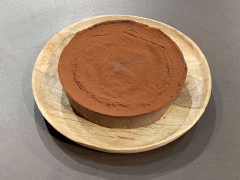 Obtention du flan pâtissier au chocolat sans pâte saupoudré de cacao en poudre, sur son plat de présentation