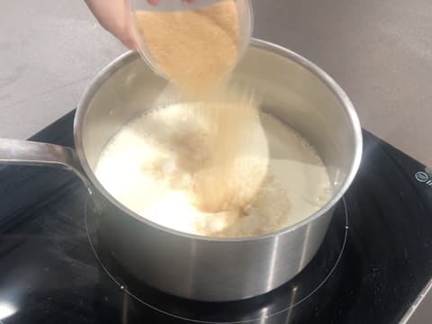 Ajout de la cassonade sur la crème liquide et le lait dans la casserole qui est posée sur la plaque de cuisson
