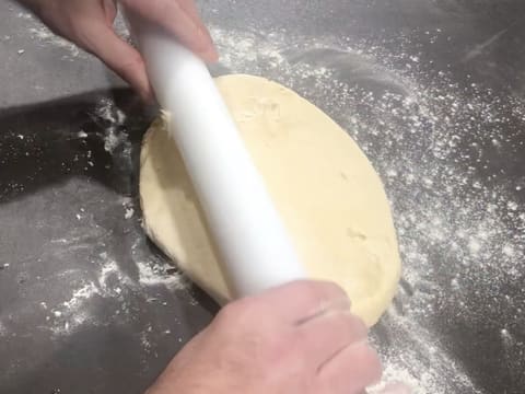 La pâte à brioche est étalée à l'aide d'un rouleau à pâtisserie, sur le plan de travail fariné