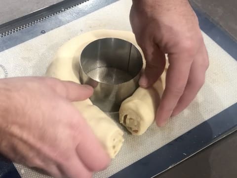 Le boudin de pâte à brioche est enroulé autour du cercle à mousse graissé qui est posé sur une plaque à pâtisserie recouverte d'un tapis de cuisson en silicone