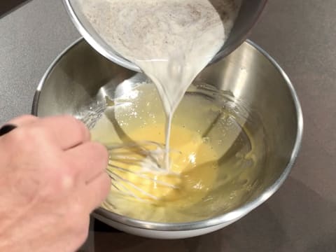 Le lait vanillé est versé dans le cul de poule qui contient le mélange à base de jaunes d'oeufs, tout en étant fouetté