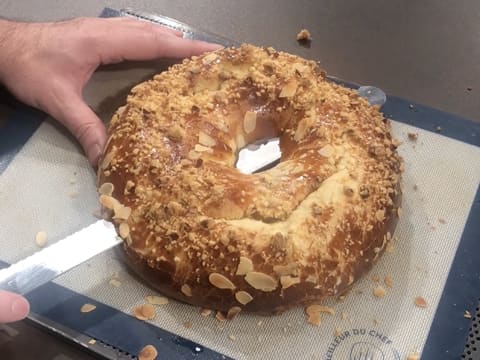 Coupe transversale de la galette des rois briochée en forme de couronne avec le couteau scie à génoise