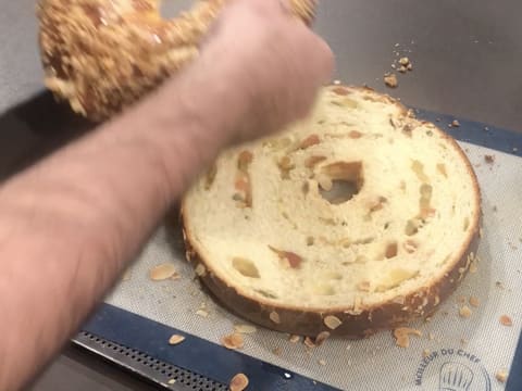 La partie haute du gâteau des rois est retirée, laissant la partie inférieure contenant les fruits confits, posée sur la plaque à pâtisserie recouverte du tapis de cuisson en silicone