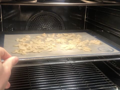 Des amandes effilées posées sur une plaque de cuisson recouverte d'un tapis en silicone sont placées à mi hauteur dans le four